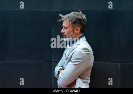 Bärtige Geschäftsmann mit Kopfhörern vor der schwarzen Wand Stockfoto