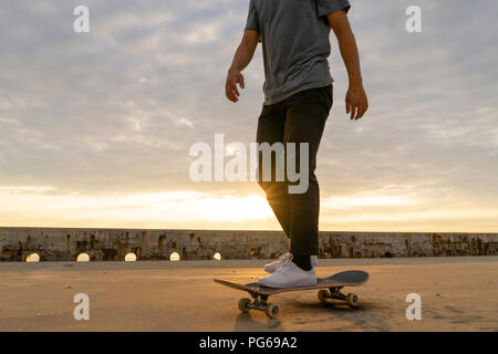 Junge Chinesen skateboarding an sunsrise nahe dem Strand Stockfoto