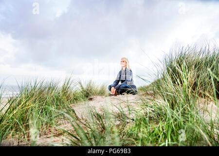 Lächelnde Frau in den Dünen sitzen Stockfoto