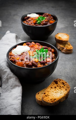 Zwei Schalen mit Chili con Carne mit frischem Koriander und saure Sahne Stockfoto