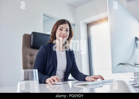 Portrait von lächelnden Jungen geschäftsfrau am Schreibtisch im Büro Stockfoto