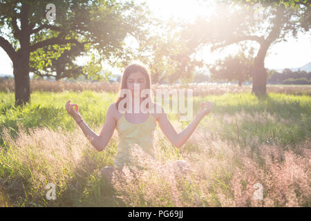 Junge Mädchen beim Nachdenken über die Wiese im Sommer Abend Stockfoto