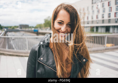 Portrait von lächelnden jungen Frau mit windswept Haar auf der Autobahn Brücke Stockfoto