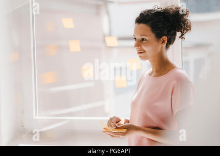 Frau buchung Haftnotizen auf Fenster, Brainstorming Stockfoto