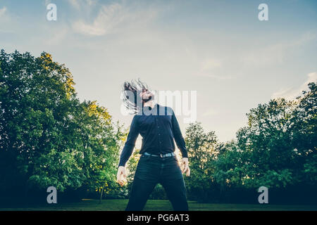 Heavy Metal Fan Headbangen in einem Park Stockfoto