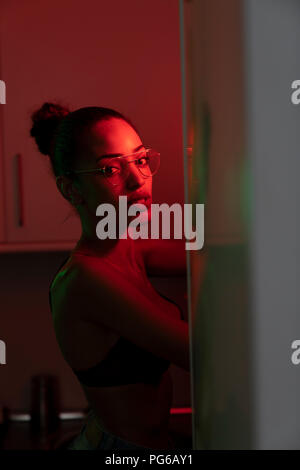 Porträt der schönen jungen Frau in Bh und Gläser in einem dunklen beleuchtete Zimmer Stockfoto