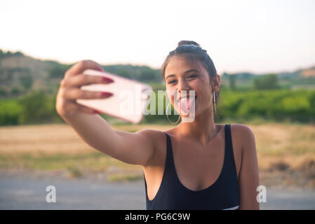 Portrait von jugendmädchen unter selfie mit Smartphone, während die Zunge Stockfoto