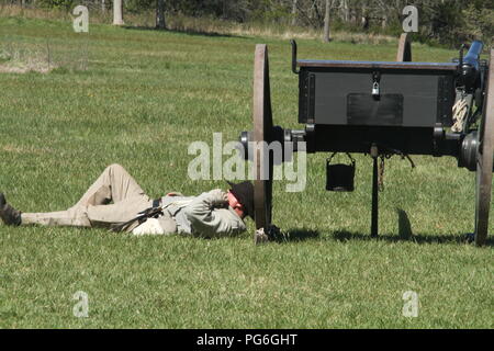Die Konföderierte Armee während des amerikanischen Bürgerkrieges. Soldat, der hinter einer Kanone ruht. Historische Nachstellung bei Appomattox, VA, USA. Stockfoto