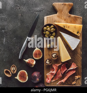 Flach mit verschiedenen Käse, Schinken, Oliven und figson dunkle Oberfläche Stockfoto