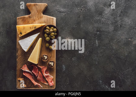 Flach mit verschiedenen Käse, Schinken und Oliven in Schale auf dunkle Oberfläche Stockfoto