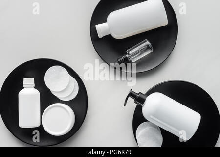 Ansicht von Flaschen mit Creme und kosmetische Pads auf drei schwarzen Platten, Schönheit Konzept Stockfoto