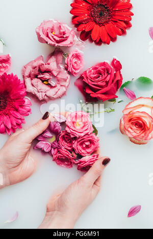 Teilweise mit Blick auf die Frau mit Rosen in den Händen Milch mit Blumenarrangements Stockfoto