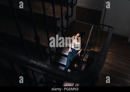 Schöne junge Frau in Treppe sitzen im Sonnenlicht Stockfoto
