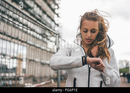 Sportliche junge Frau im freien Blick auf Uhr Stockfoto