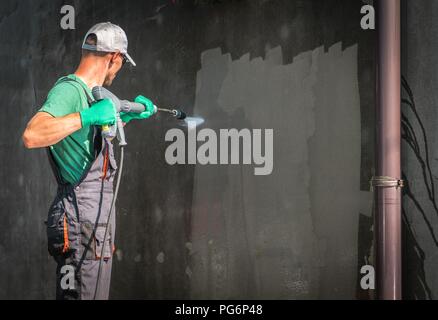 Gebäude Höhe Waschen unter Druck durch Arbeiter mit Hochdruckreiniger. Erfrischende Haus außerhalb der Stadtmauern. Stockfoto