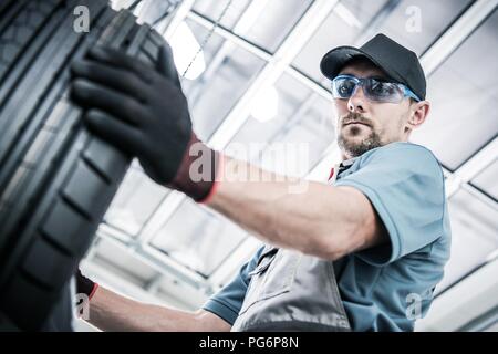 Neue Reifen kaufen. Kaukasische Store Arbeiter auf der Suche nach richtigen Reifen. Saisonale Wartung des Fahrzeugs. Stockfoto