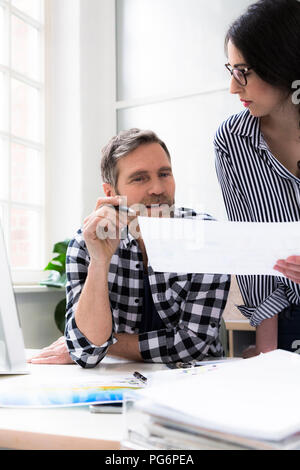 Kollegen diskutieren Dokument am Schreibtisch im Büro Stockfoto