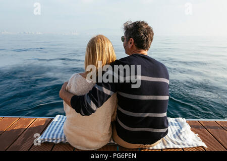 Reifes Paar sitzt auf Jetty, Entspannen am Meer Stockfoto