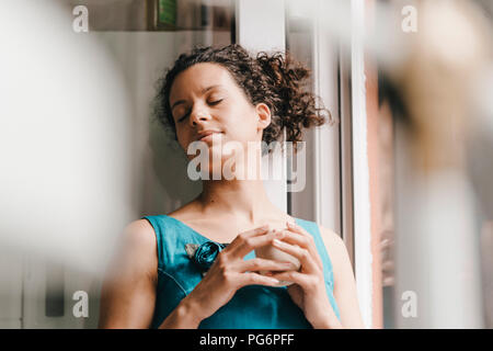 Hübsche Frau lehnte sich auf Fenster, trinken Kaffee Stockfoto