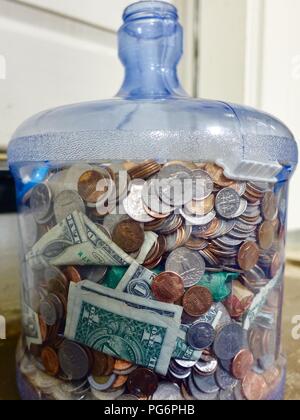 Zwei Liter Wasser Flasche mit sortierten uns Münzen gefüllt, ein paar Dollarscheine. Stockfoto