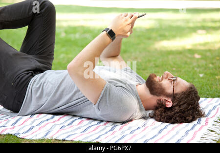 Mann liegen auf Decke in einem Park mit Handy Stockfoto