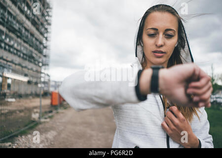 Sportliche junge Frau im freien Blick auf Uhr Stockfoto