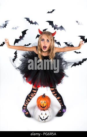 Kleines Mädchen mit einem Dämon Teufel Kostüm in schwarz rot Kleid und roten Teufel Hörner für Pumpkin Patch und Halloween Party gekleidet, mit glücklich smi Posing Stockfoto