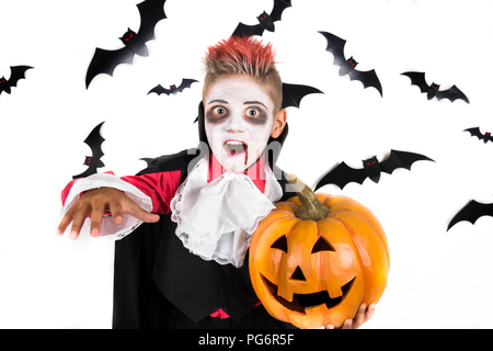 Scary Halloween vampir Boy für gruselige Halloween Party gekleidet und eine orange halloween kürbis jack o lantern Holding Stockfoto