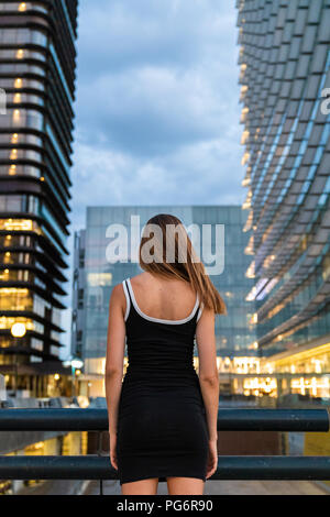 Ansicht der Rückseite des junge Frau mit schwarzen Kleid in die Stadt in der Dämmerung Stockfoto