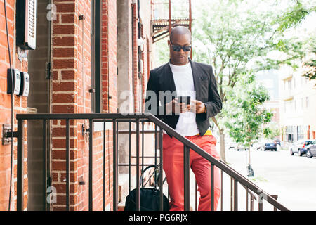 USA, New York City, Brooklyn, Mann warten auf Treppen, mit Smartphone Stockfoto