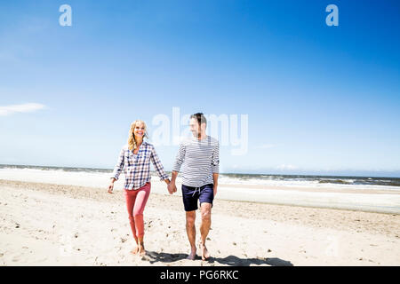 Paare, die Hand in Hand am Strand Stockfoto