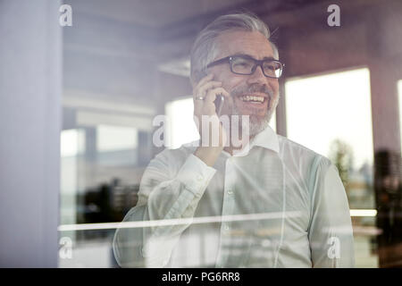 Lachend Geschäftsmann am Fenster Gespräch am Handy Stockfoto