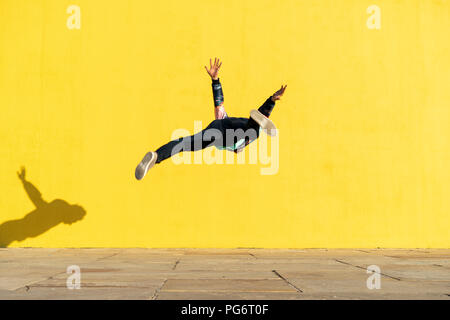 Acrobat springen Purzelbäume vor der gelben wand Stockfoto