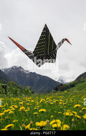 Origami Kranich fliegen über Wiese Stockfoto