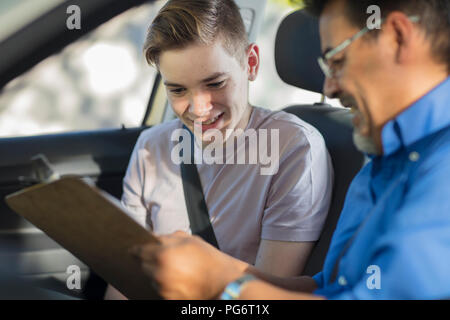 Fahrschüler mit Ausbilder im Auto auf der Suche nach test Script Stockfoto