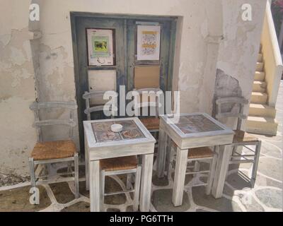 Griechenland - Kykladen, schöne Insel Kythnos. Die farbenfrohe traditionelle Hauptstadt (hora). Tische und Stühle in einer Gasse an einer Bar in der Altstadt. Stockfoto