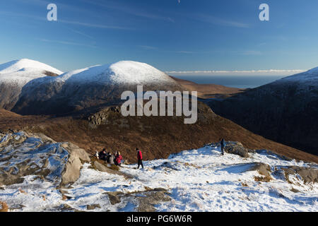 Gruppe von Winter hillwalkers genießen einen Rest auf Doan Berg. Blick auf Ben Crom direkt vor und schneebedeckten Lamagan hinter sich. Slieve Donard auf der linken Seite. Stockfoto