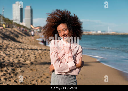 Portrait von lächelnden schöne junge Frau mit Afro Frisur stehen auf dem Strand Stockfoto