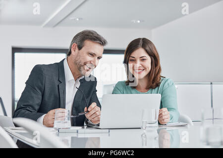 Kaufmann und Kauffrau in einer Sitzung im Büro mit Laptops Stockfoto