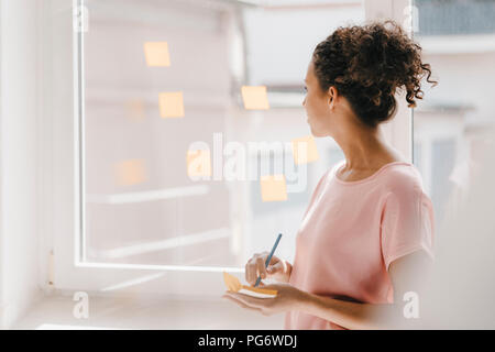 Frau buchung Haftnotizen auf Fenster, Brainstorming Stockfoto