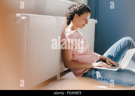 Frau sitzt auf dem Boden, mit Laptop Stockfoto