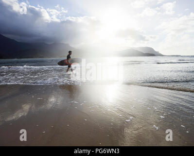 USA, Hawaii, Kauai, Hanalei Bay Resort, Mann am Strand mit Surfbrett Stockfoto