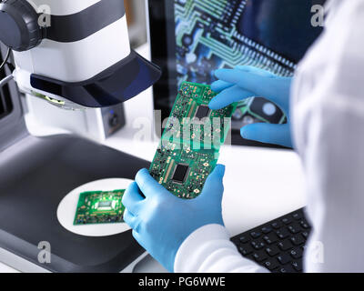 Techniker mit Hilfe eines 3-D Stereo Mikroskop für die Qualitätskontrolle in der Herstellung von Platinen für die Elektronikindustrie Stockfoto