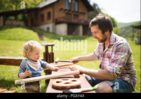 Vater und Sohn arbeiten mit einem Hammer im Garten Stockfoto