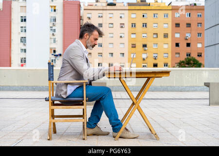 Unternehmer sitzen auf der Dachterrasse Arbeiten am Laptop Stockfoto