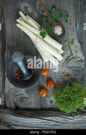 Weißer Spargel, Petersilie, Kresse, Salz und gemischte Pfefferkörner auf Holz Stockfoto