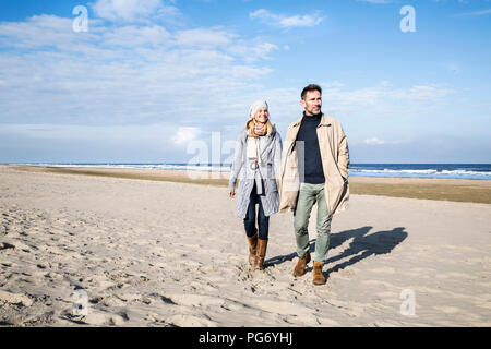 Paar in warme Kleidung zu Fuß am Strand Stockfoto