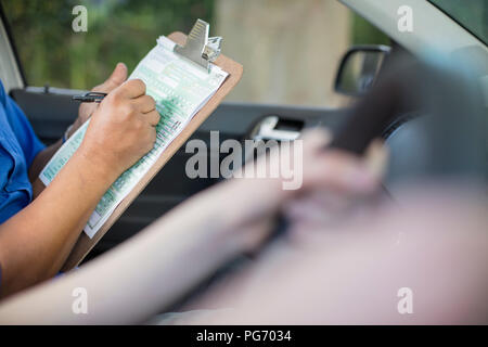 Nahaufnahme der Inspektor im Auto schreiben auf Test Script Stockfoto