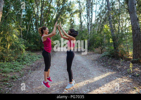 Zwei aktive Frauen hoch fiving im Wald Stockfoto