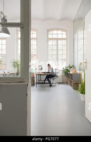 Frau Arbeiten am Schreibtisch in einem Loft Büro Stockfoto